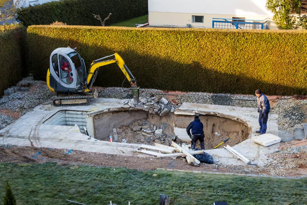 on a private swimming pool construction is dismantled by an excavator